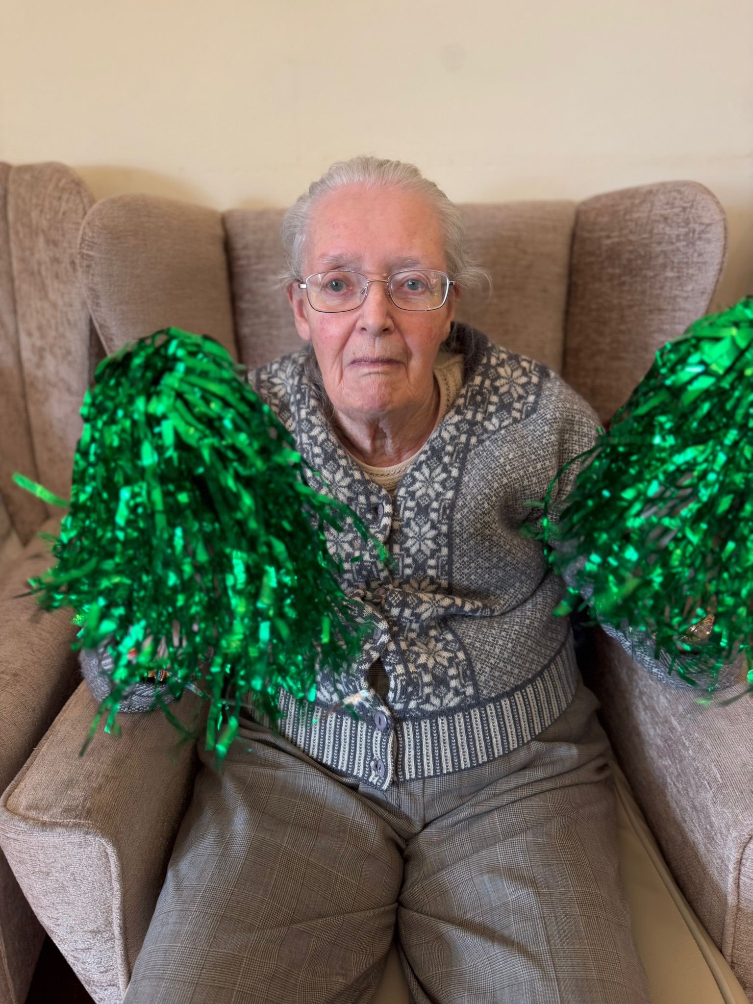 Female resident seated holding two green sparkly pompoms