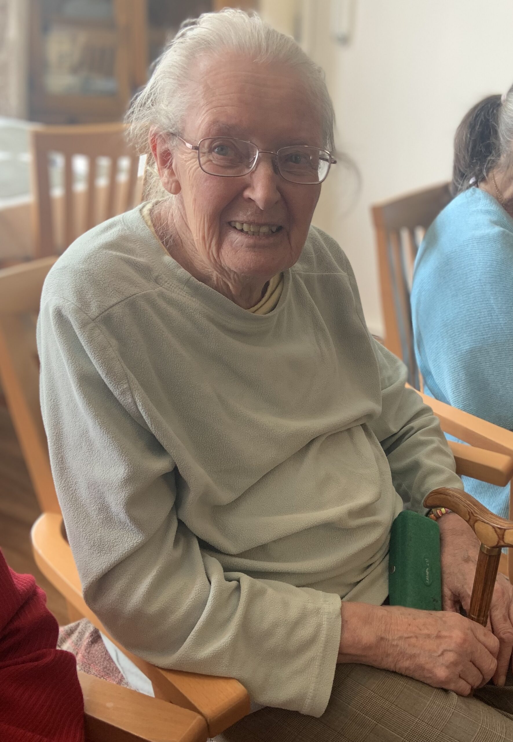 Female resident seated smiling for a photo scaled