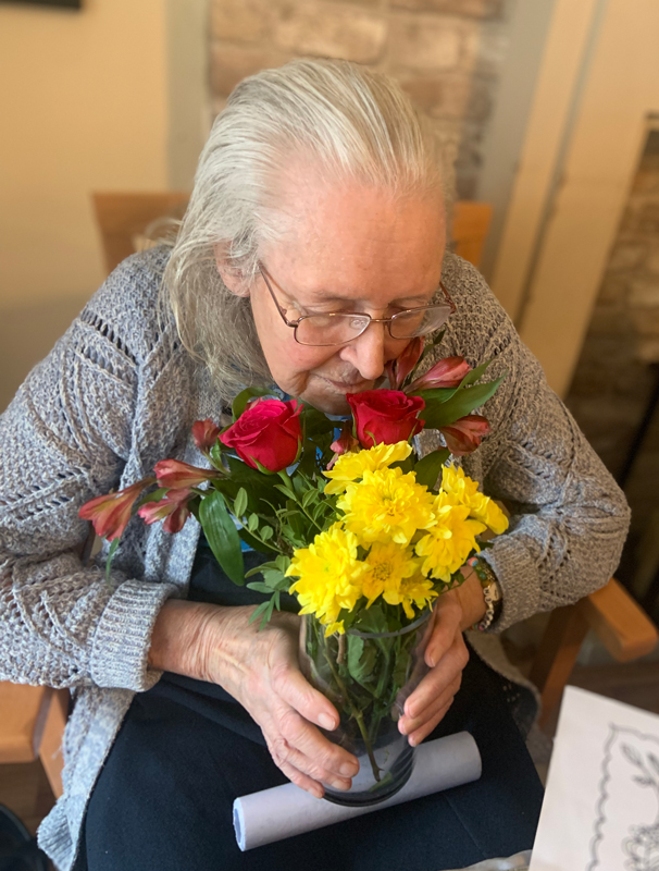 Female resident smelling her vase of flowers smiling