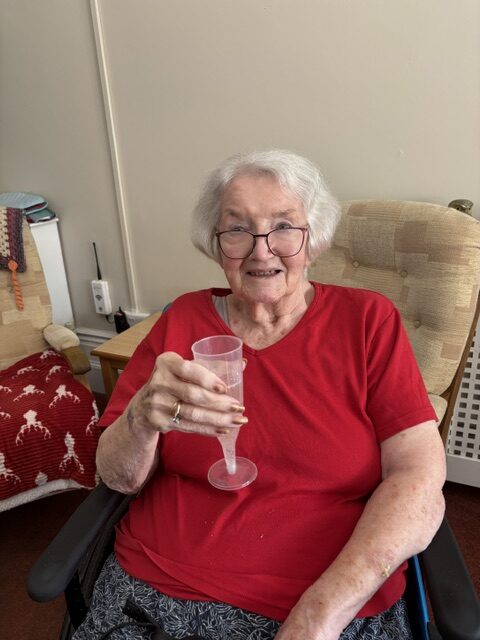 Female resident smiling enjoying for glass of bubbly rotated