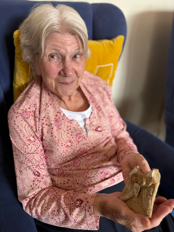 Female resident smiling holding her pottery owl