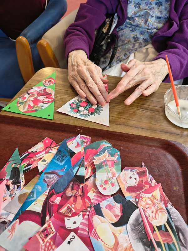Female resident sticking a picture of red and white rose bush to paper bunting