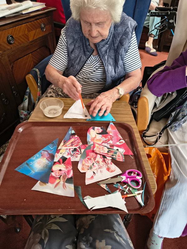 Female resident using a brush to put glue onto paper bunting