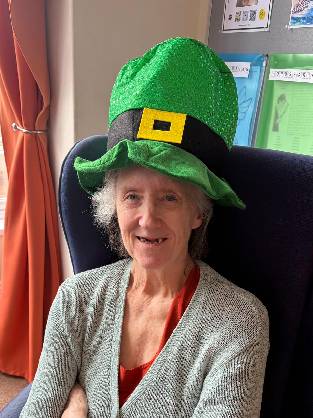 Female resident wearing a leprechaun hat smiling