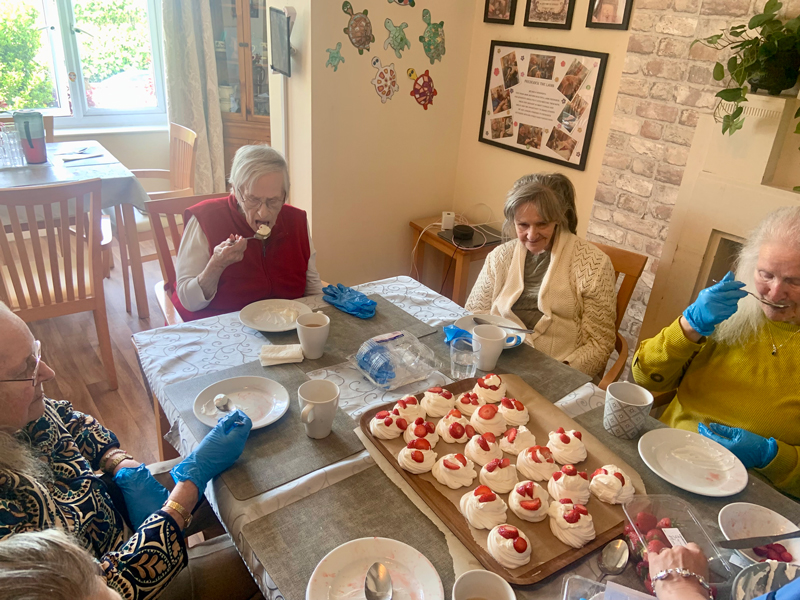Finished pavlovas in the middle of the table with residents sampling them too