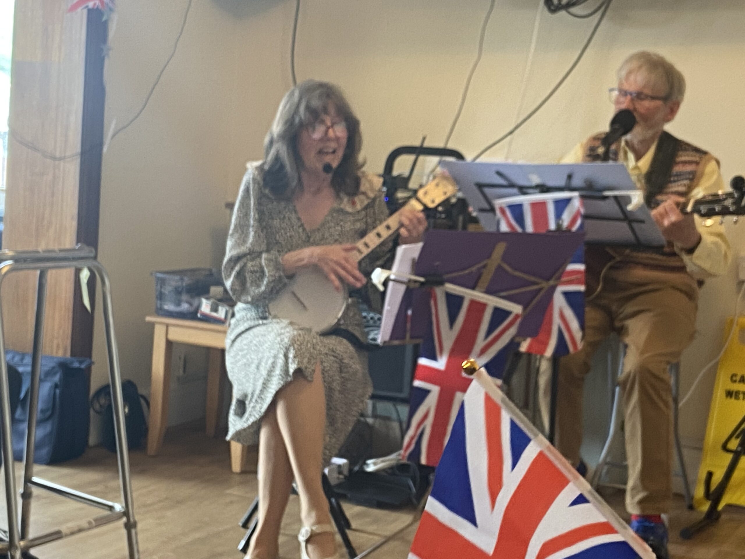 Glenis singing and playing the banjo with a partner on guitar singing scaled