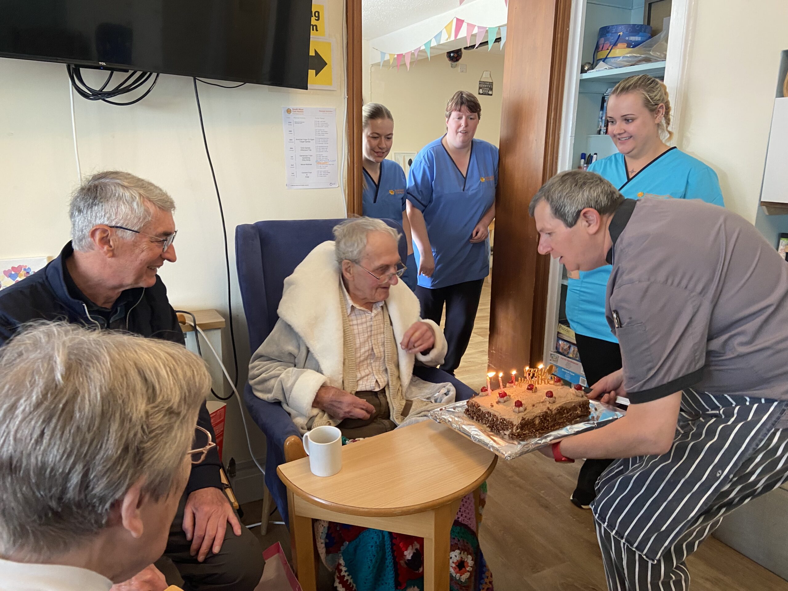 Gordon blowing out the candles on his cake with family and carers scaled