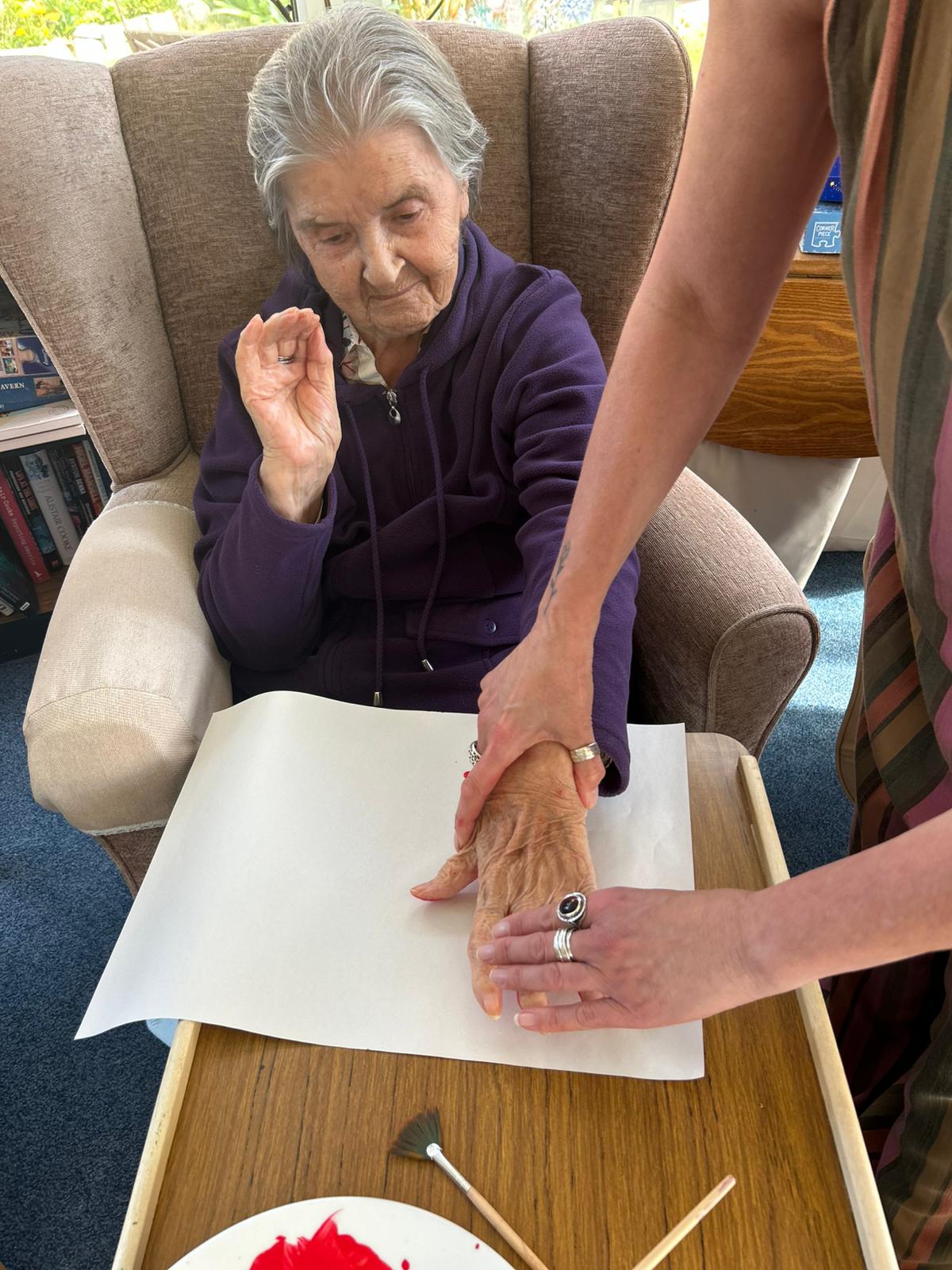 Herta pressing her red painted hand onto paper