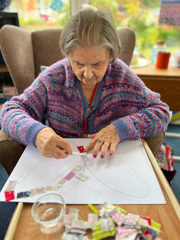 Herta working on her butterfly patchwork sticking on squares of paper
