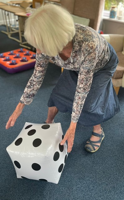 Jean rolling a large blow-up dice along the floor Jean rolling a large blow up dice along the floor