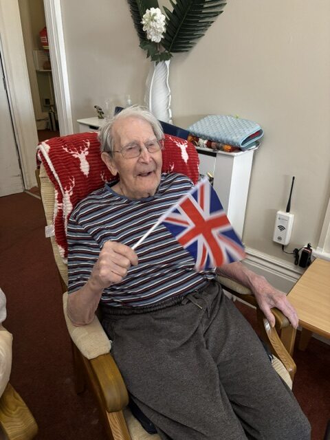 Male resident listening to Zara waving his flag smiling rotated
