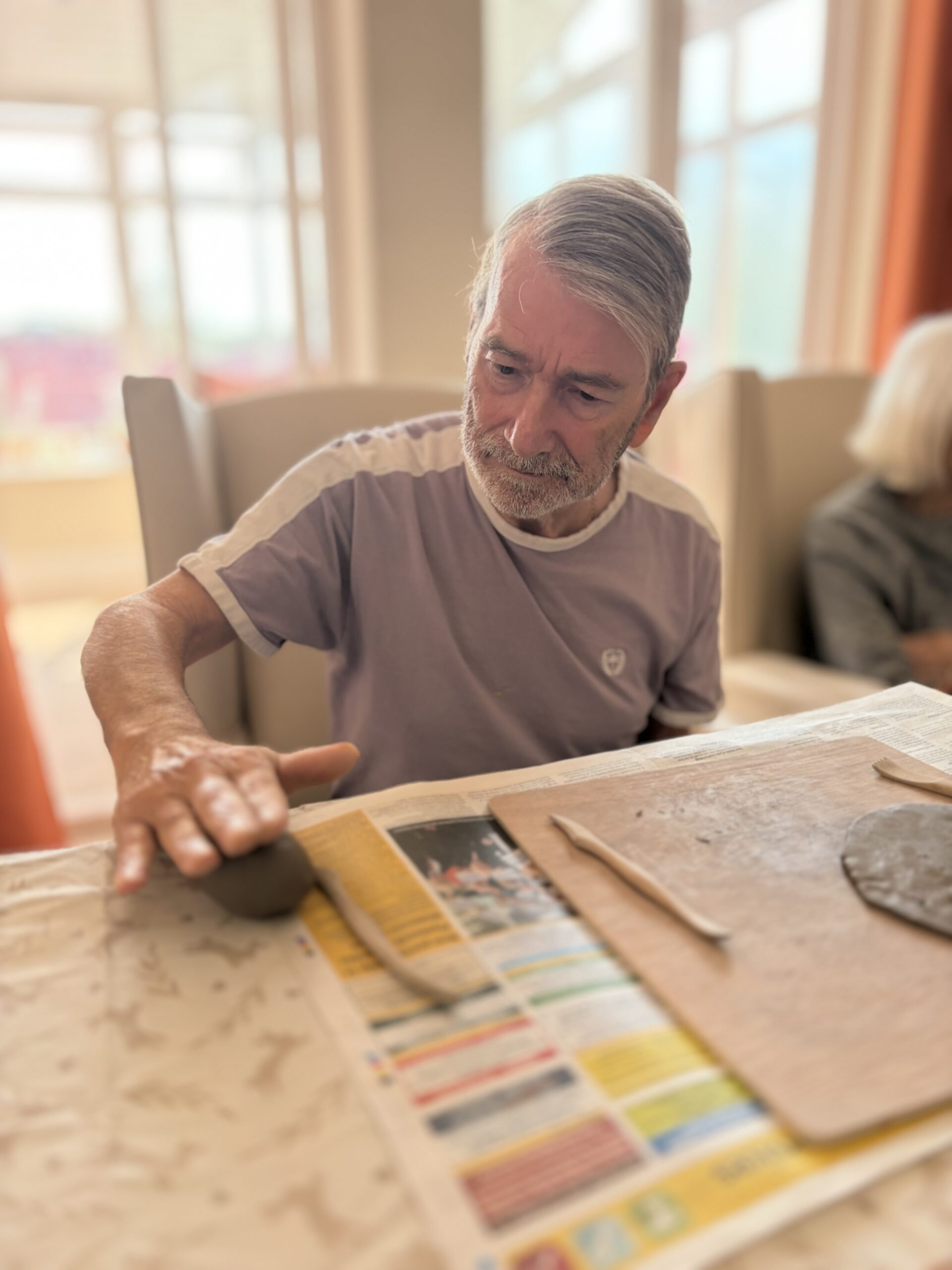 Male resident rolling a piece of clay with the palm of his hand scaled