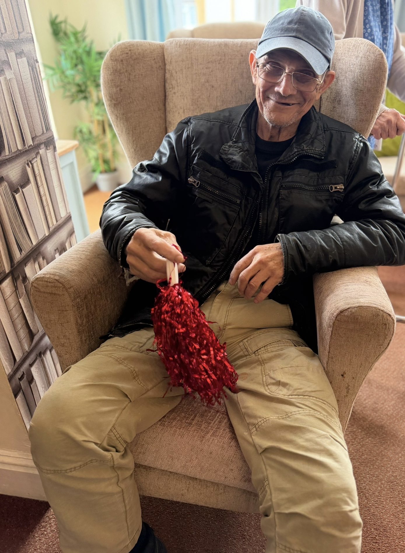 Male resident seated holding a red shiny pompom