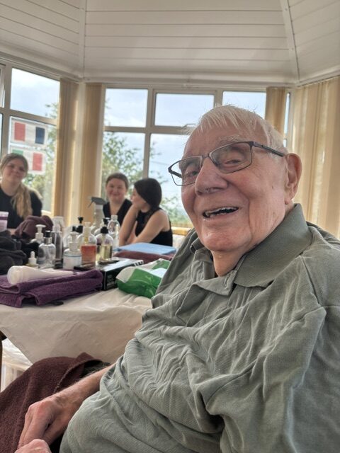 Male resident seated in the conservatory relaxed and smiling after his massage rotated