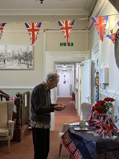 Male resident standing at a table of WW2 memorabilia reading an info sheet rotated
