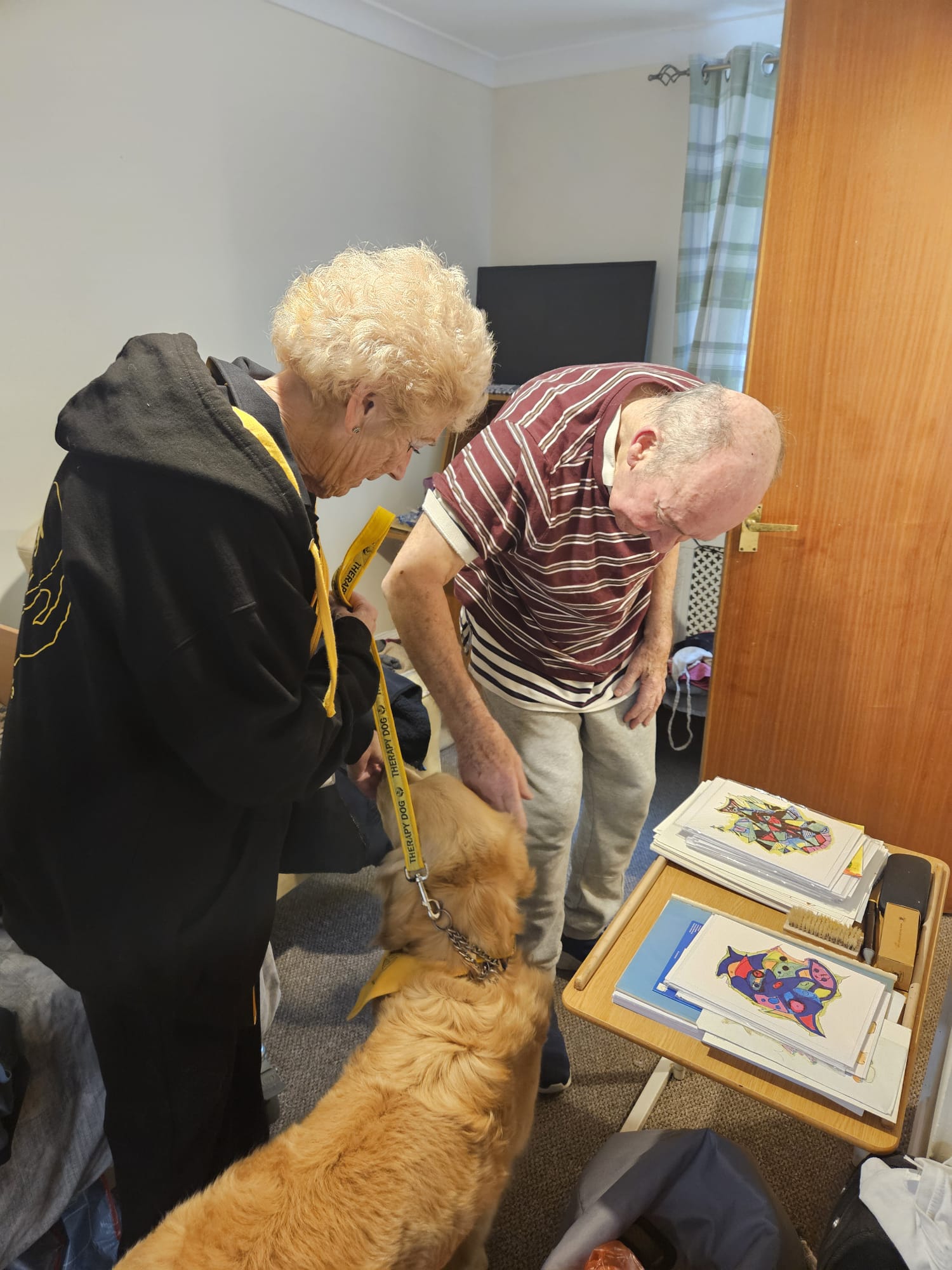 Male resident standing in his room stroking Bimble with Bibles carer