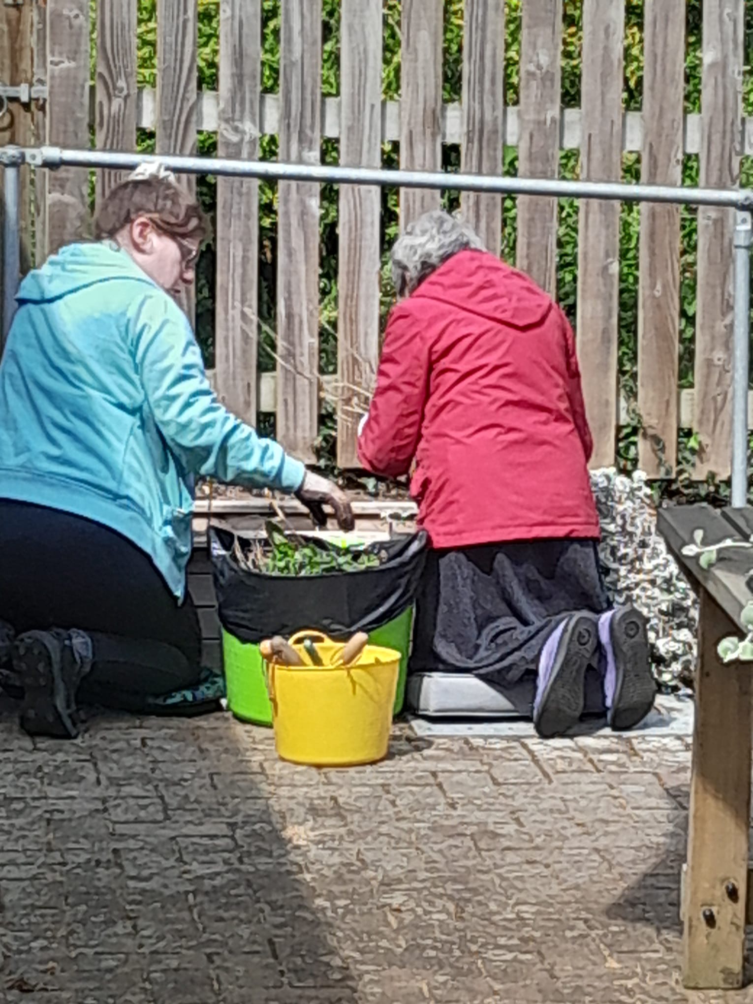 Marj and carer kneeling in front of a planter adding plants