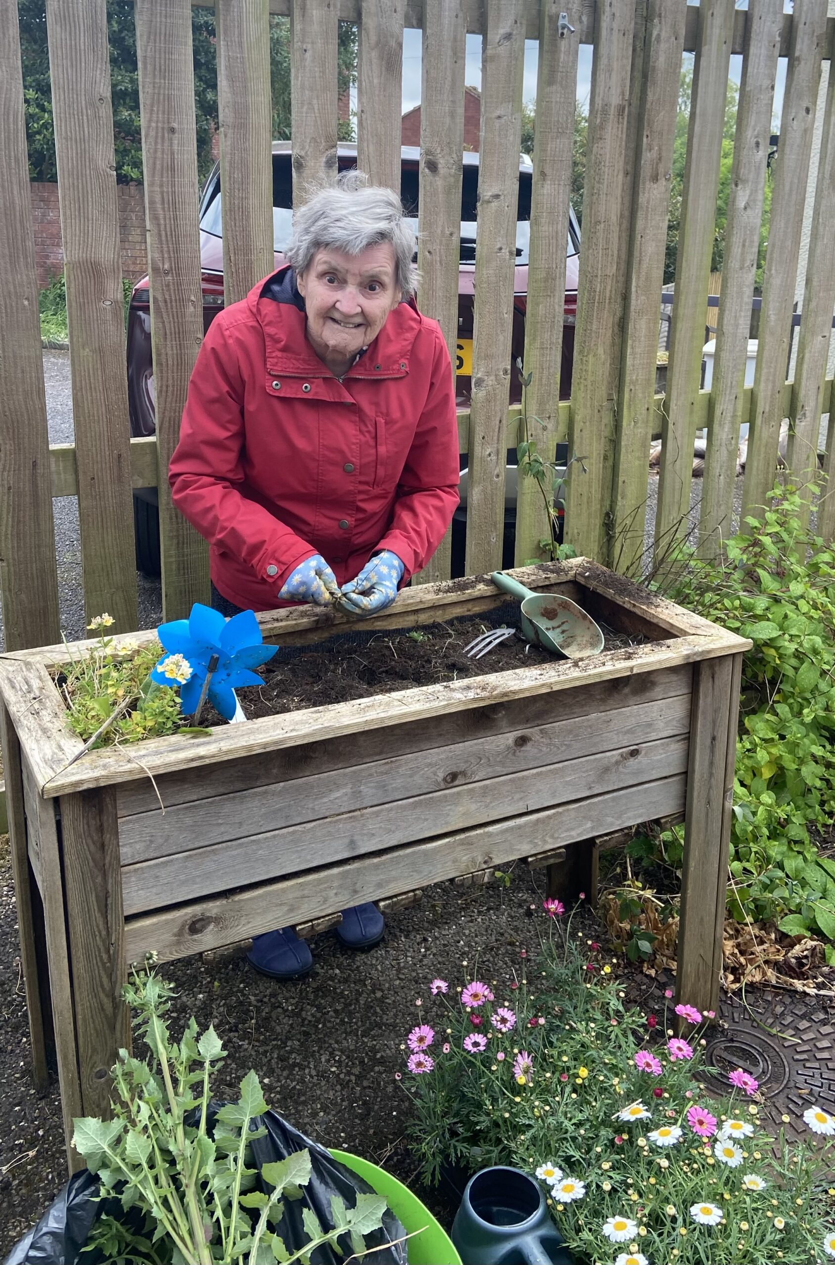 Marj smiling clearing out a large free standing planter scaled