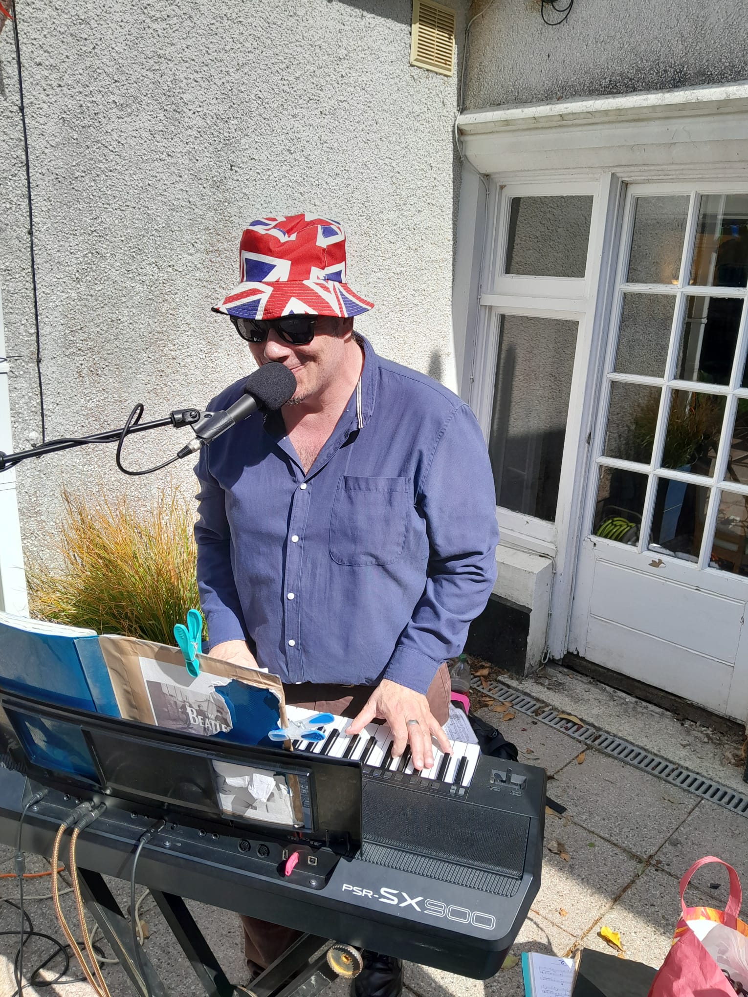 Neil Tebay singing and playing a keyboard outside in the sunshine