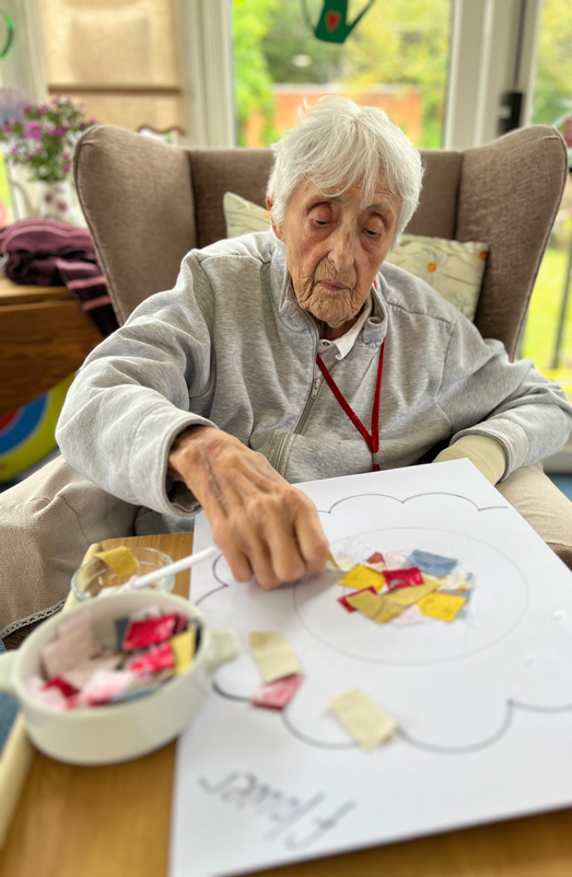 Pauline sticking squares on paper onto her flower shape patchwork