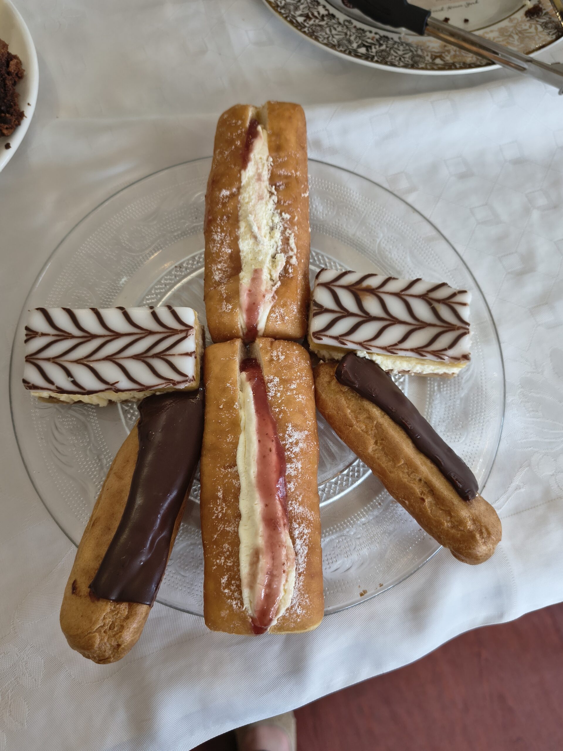 Plate of cakes eclairs jam and cream bun icing slice scaled
