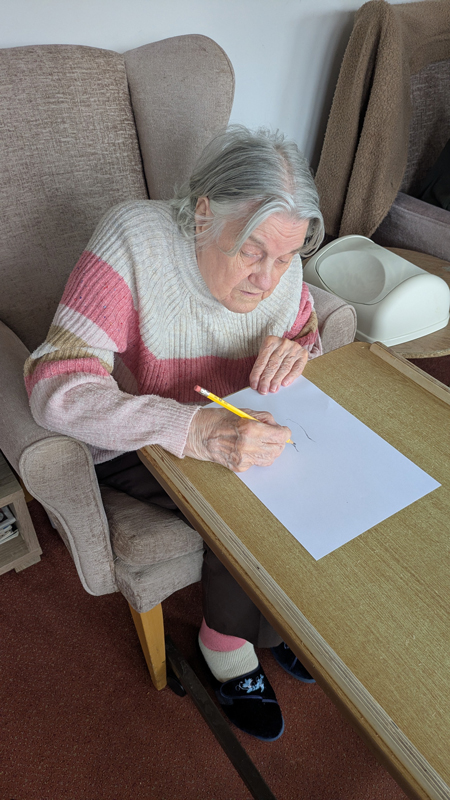 Resident starting their drawing of the flowers in pencil