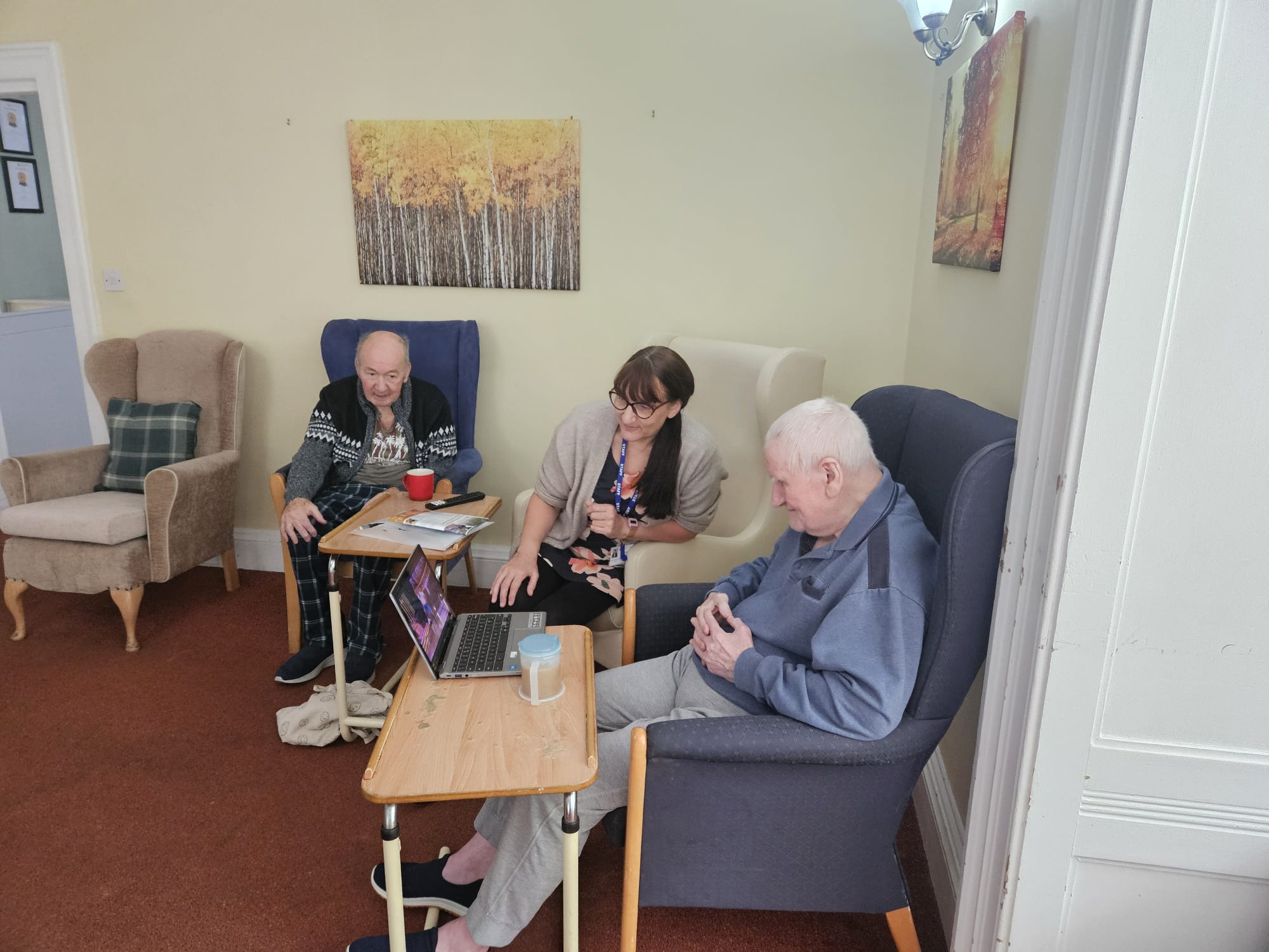 Residents and a staff member seated around a laptop watching a video