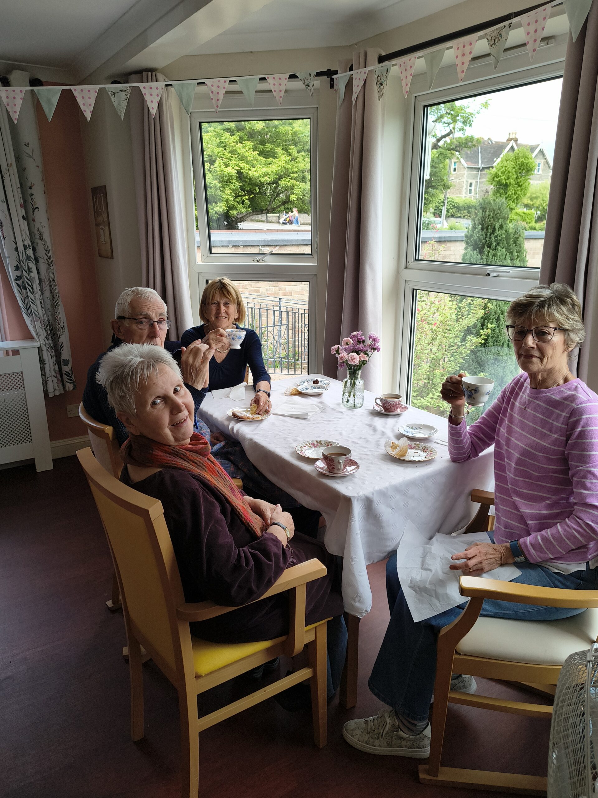Residents family seated around a table enjoying tea and cake scaled