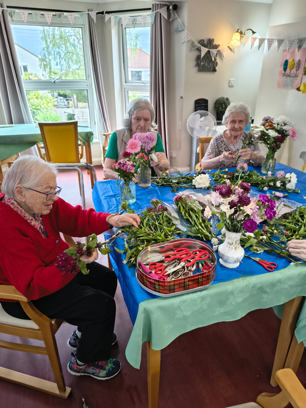 Residents seated around a table full of cut flowers