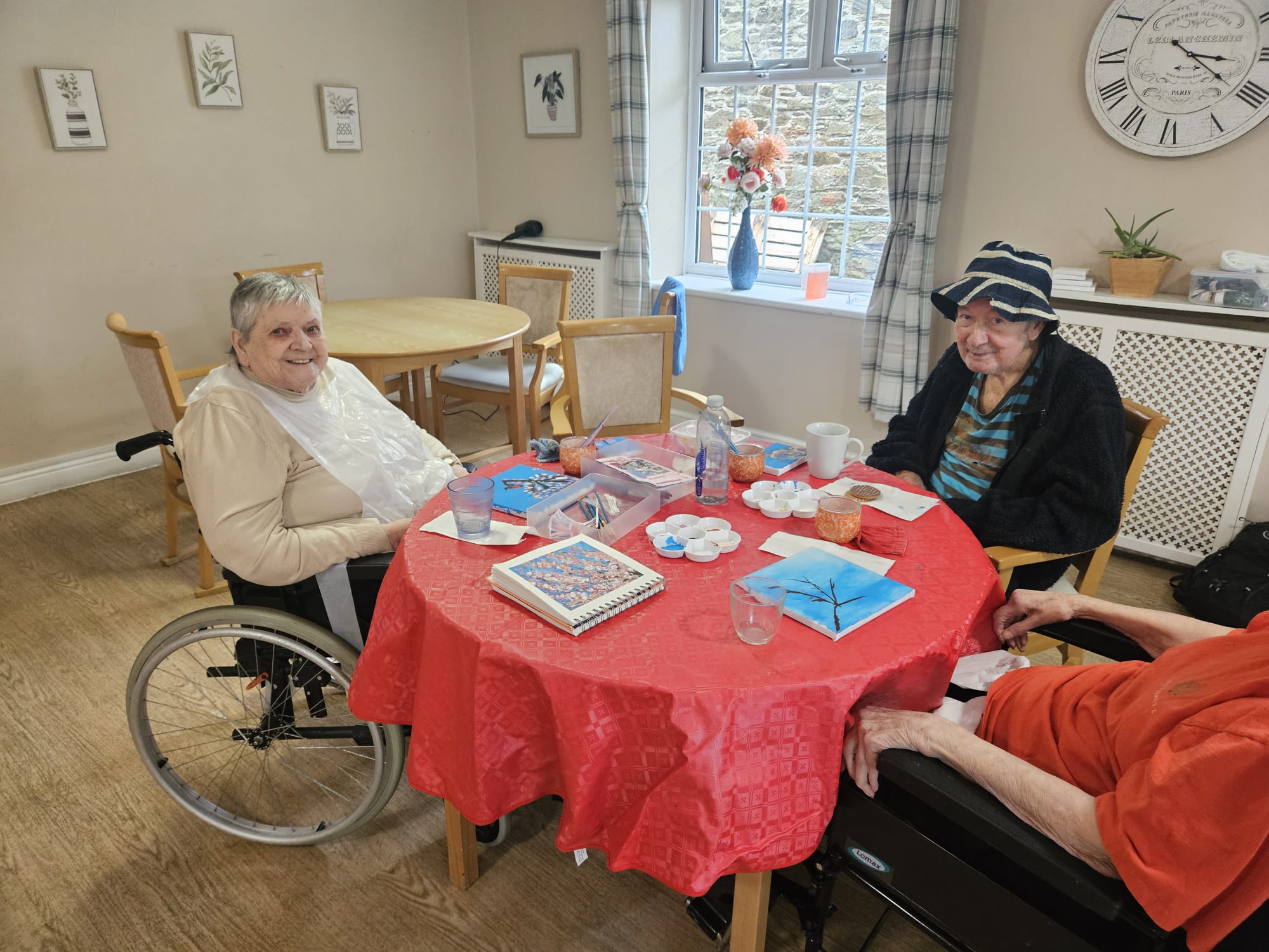 Residents seated around a table painting blossom