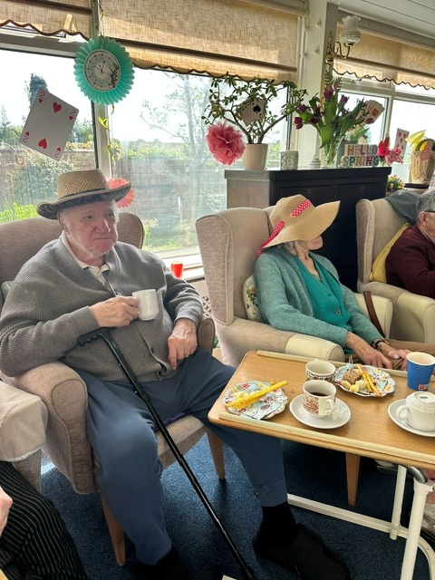 Residents seated in the conservatory enjoying tea and cake 