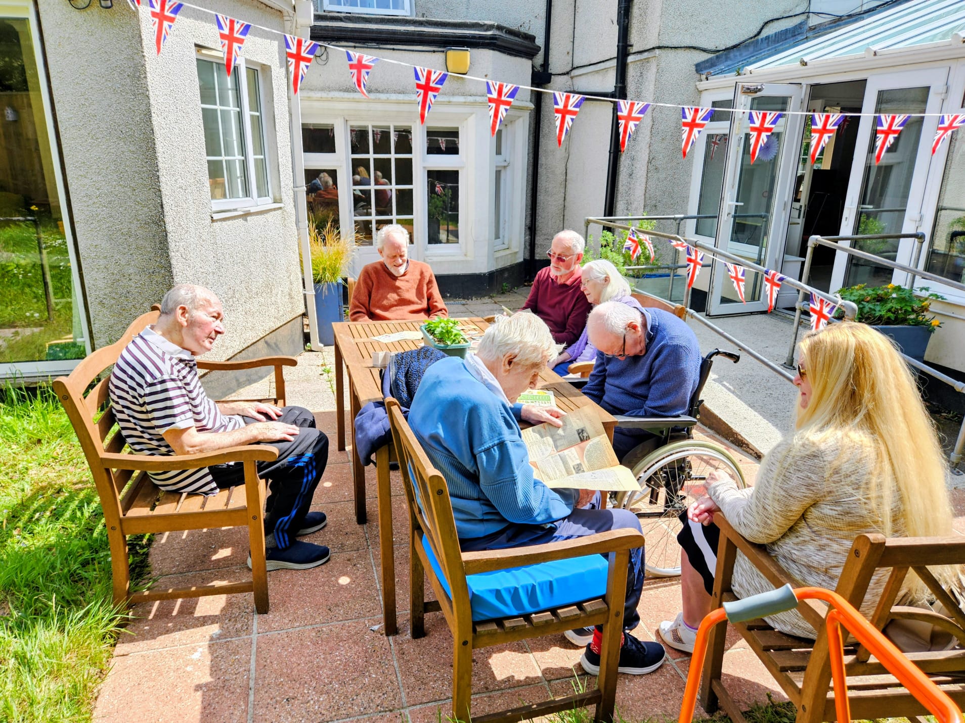 Residents seated outside around a table in the sun looking at WW2 memorabilia