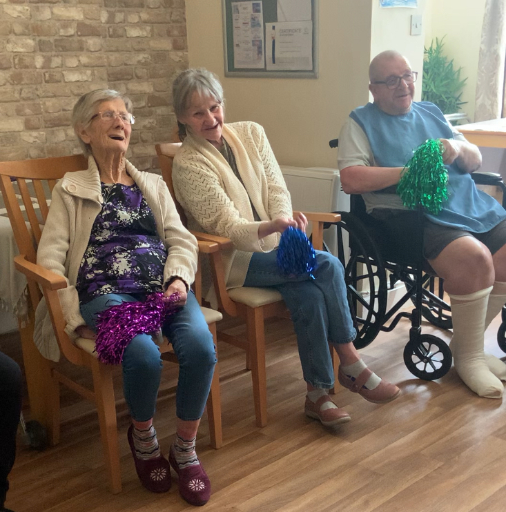 Residents smiling and singing along waving pompoms
