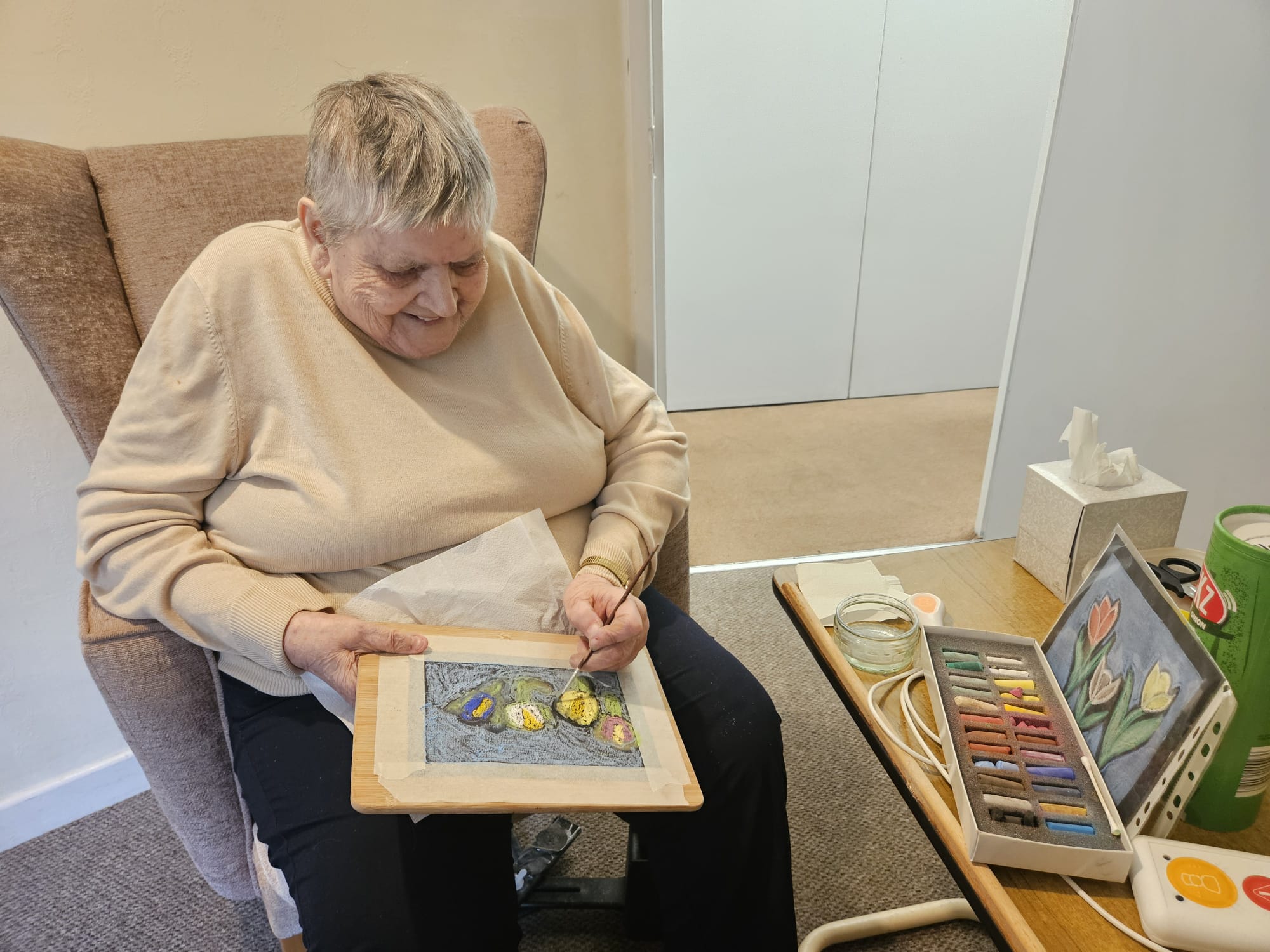 Sandra adding water to her pastel drawing with a brush