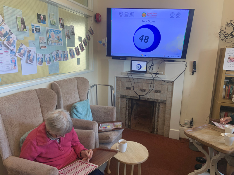 Seated resident with screen showing a bingo ball number