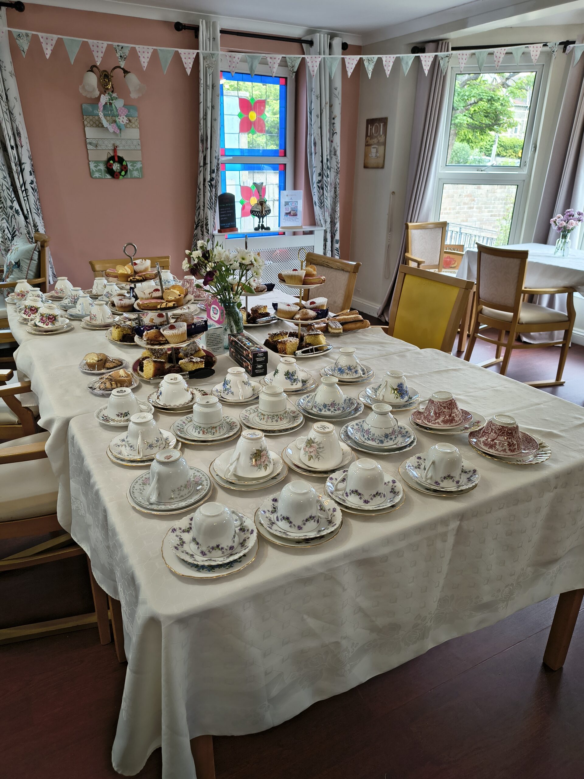 Table laid out with cups and saucers and cakes scaled