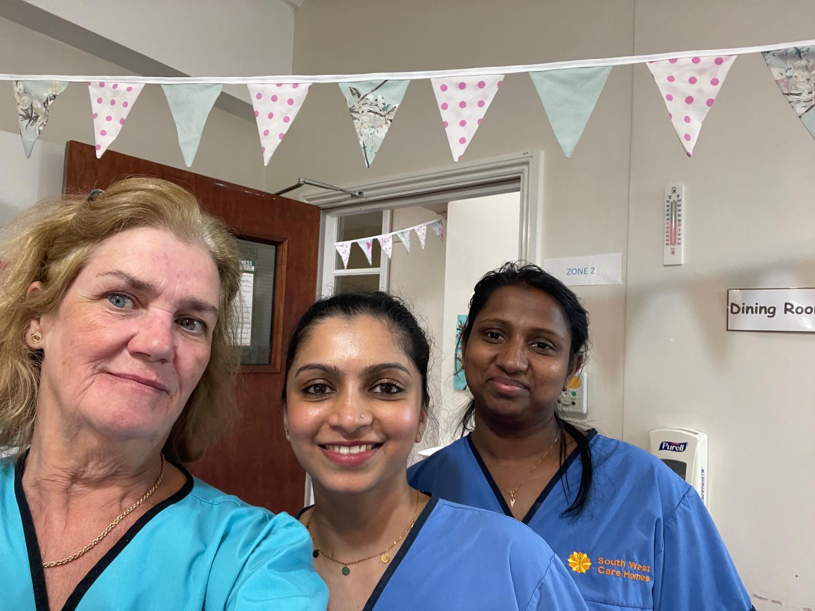 Three carers taking a selfie with bunting around the room