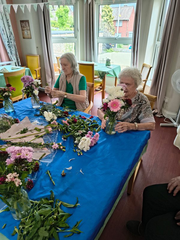 Two female residents placing flowers into vases