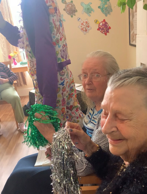 Two female residents seated beside Paul smiling enjoying the music