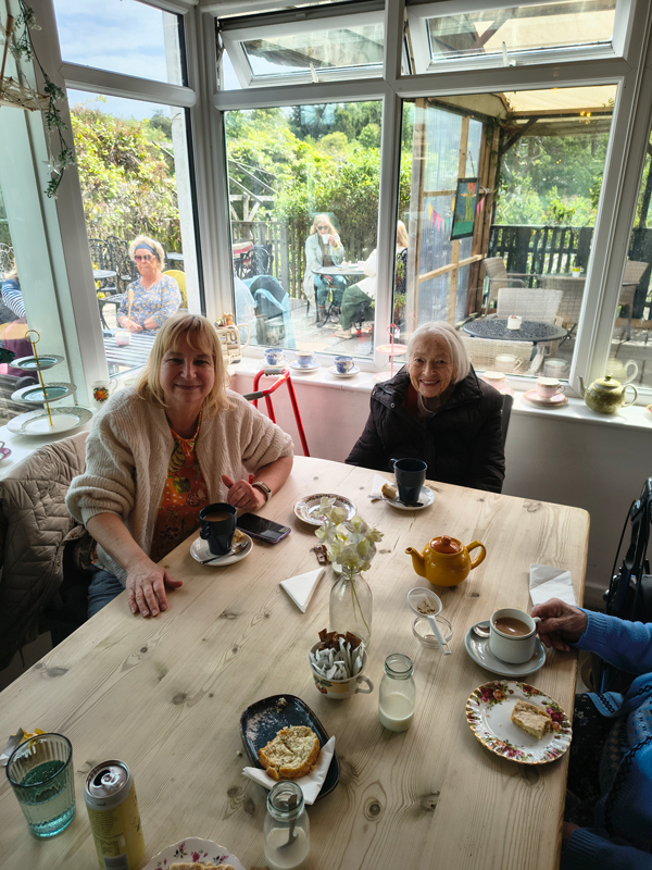 Two female residents seated in the cafe enjoying coffee and cake