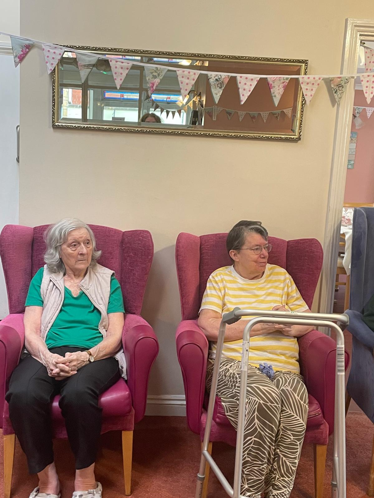 Two residents seated watching on