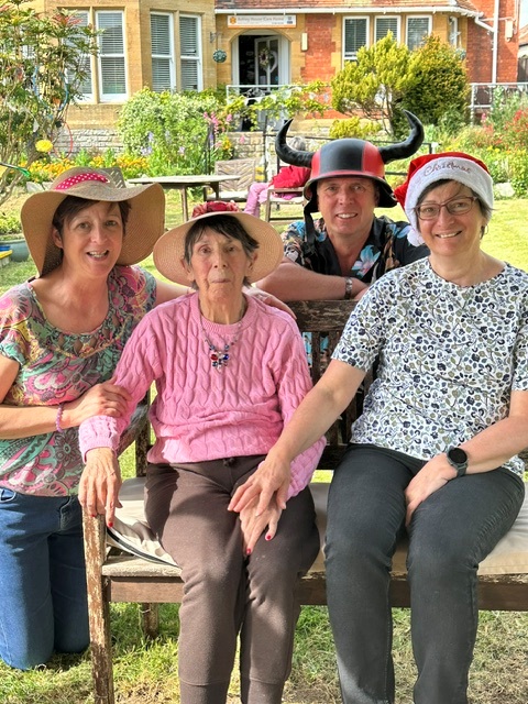 Violet and her family sitting outside on a bench with hats on