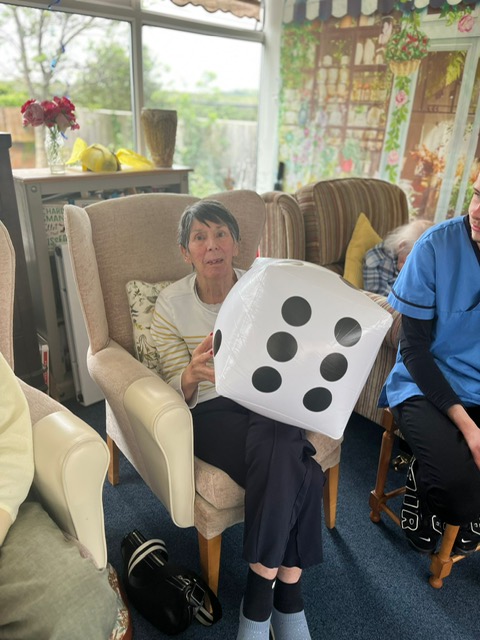 Violet seated holding a large blow-up dice Violet seated holding a large blow up dice
