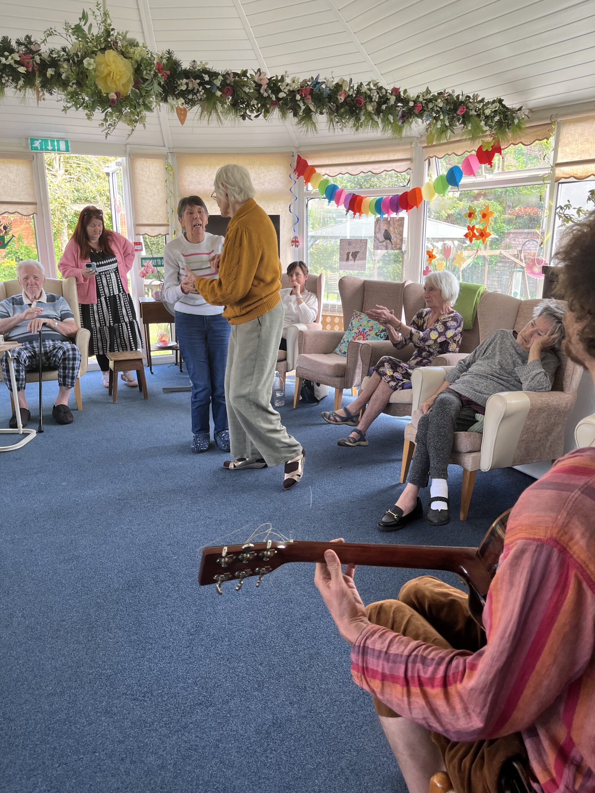 Wendy and Violet dancing while other residents clap scaled