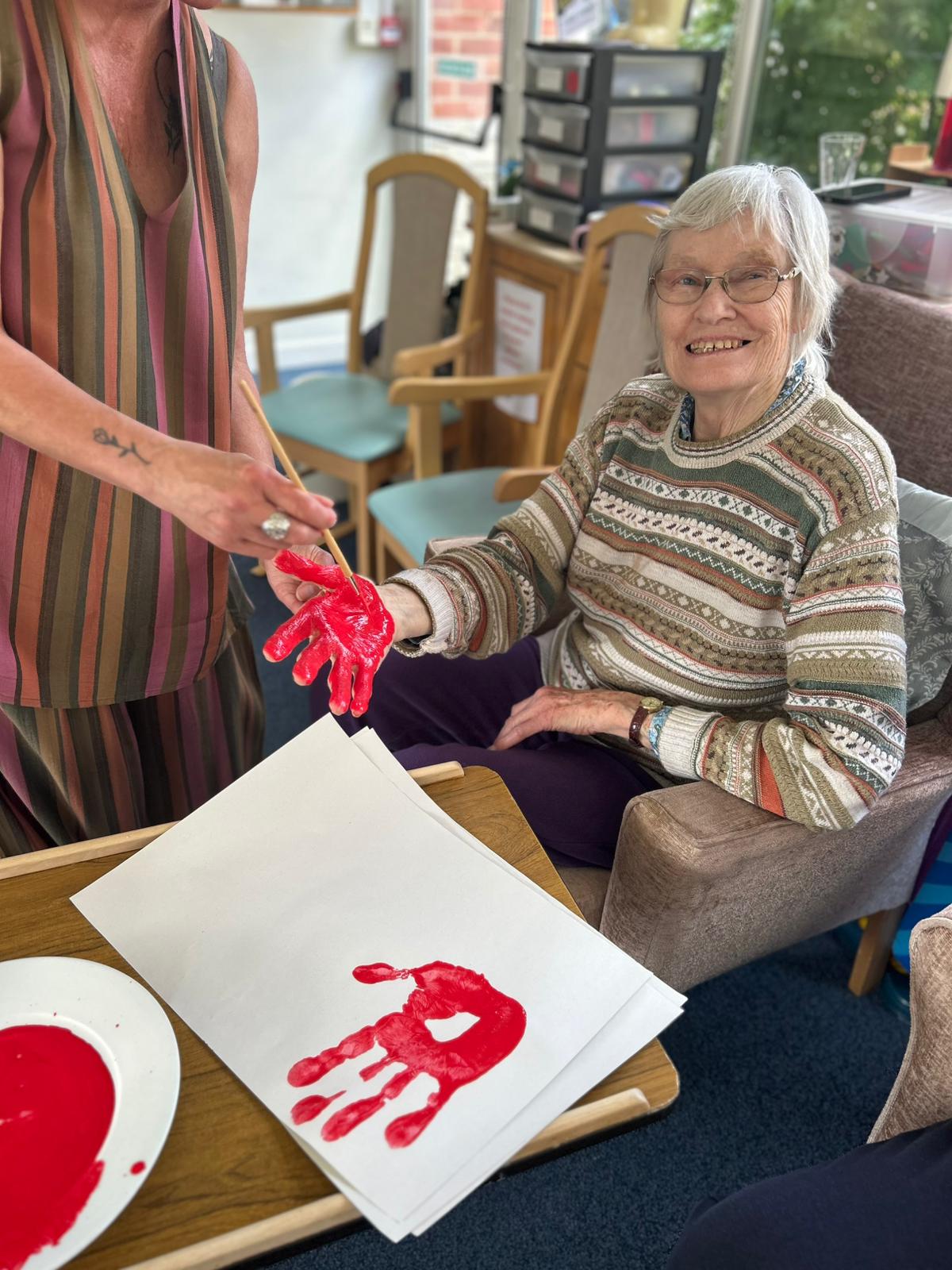 Wendy having her hand painted red ready to print smiling