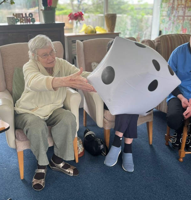 Wendy seated throwing a large blow-up dice Wendy seated throwing a large blow up dice