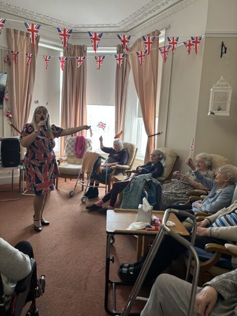 Zara singing to seated residents waving Union Jacks rotated